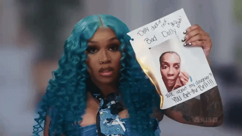 A Woman With Blue Hair Is Holding A Piece Of Paper That Says " Bad Doll " GIF