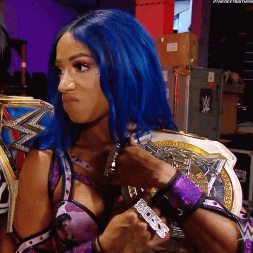 A Woman With Blue Hair Is Holding A Wrestling Championship GIF