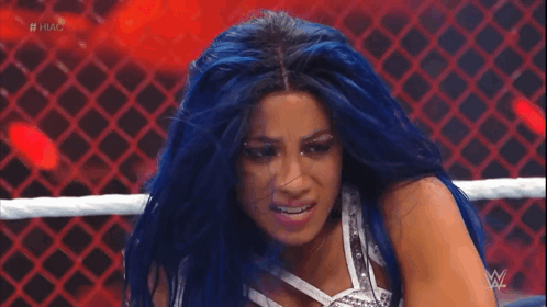 a woman with blue hair is in a wrestling ring with the hashtag #hug on the screen