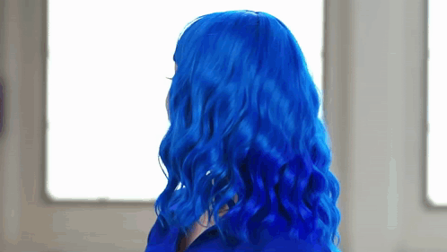 A Woman With Blue Hair Is Looking Out A Window . GIF