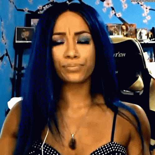 A Woman With Blue Hair Is Making A Funny Face While Wearing A Polka Dot Top . GIF