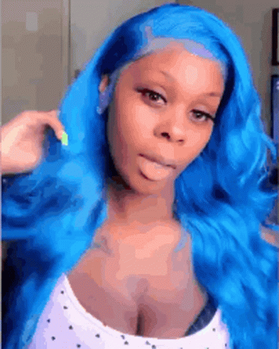 A Woman With Blue Hair Is Making A Funny Face While Wearing A White Tank Top . GIF