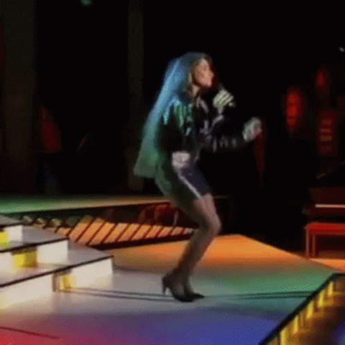 A Woman With Blue Hair Is Singing Into A Microphone GIF