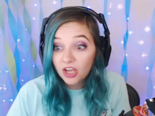 A Woman With Blue Hair Is Wearing Headphones And Making A Face . GIF