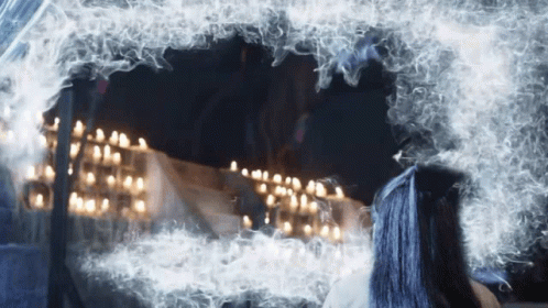 a woman with blue hair looks at herself in a mirror