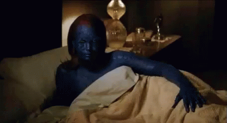 A Woman With Blue Paint On Her Face Is Laying In Bed . GIF