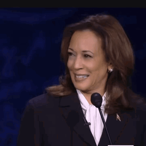 A Woman With Braces On Her Teeth Is Laughing While Speaking Into A Microphone GIF