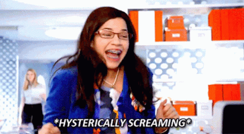 A Woman With Braces On Her Teeth Is Screaming Hysterically In An Office GIF
