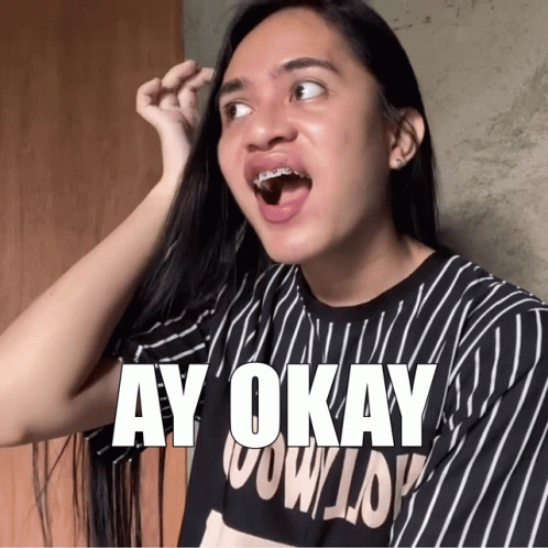 A Woman With Braces On Her Teeth Is Wearing A Black And White Striped Shirt That Says Ay Okay GIF