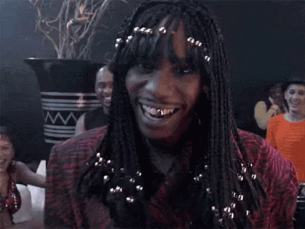 A Woman With Braids And A Ring On Her Finger Is Smiling And Making A Funny Face . GIF