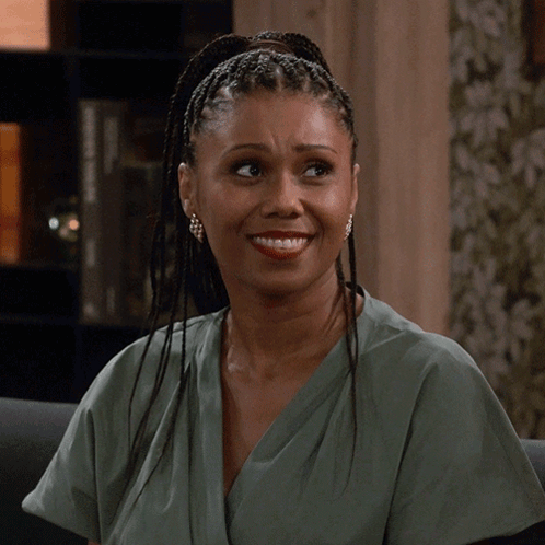 A Woman With Braids And Earrings Is Smiling GIF