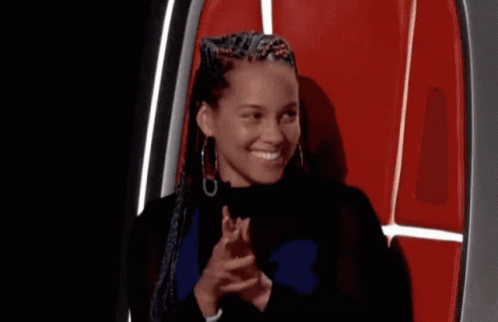 A Woman With Braids Is Sitting In A Chair Covering Her Mouth With Her Hand . GIF