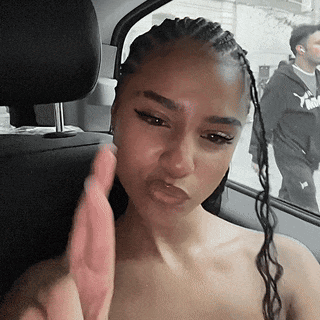 A Woman With Braids Is Sitting In The Back Seat Of A Car Making A Face . GIF