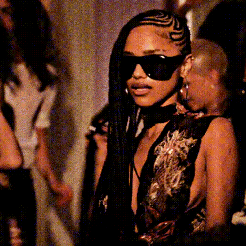 A Woman With Braids Wearing Sunglasses And A Choker Around Her Neck GIF
