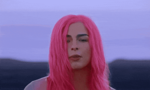 A Woman With Bright Pink Hair Is Looking At The Camera . GIF