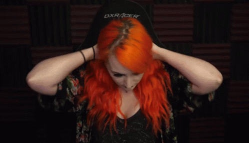A Woman With Bright Red Hair Is Holding Her Hair In Her Hands . GIF