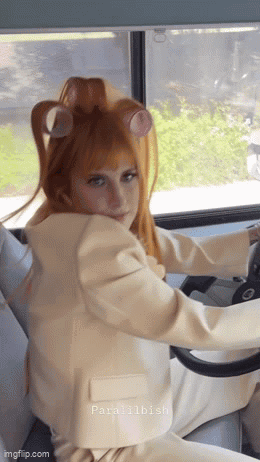 A Woman With Curlers In Her Hair Is Driving A Car GIF