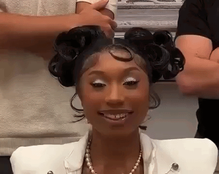 a woman with curlers in her hair is smiling while getting her hair done .