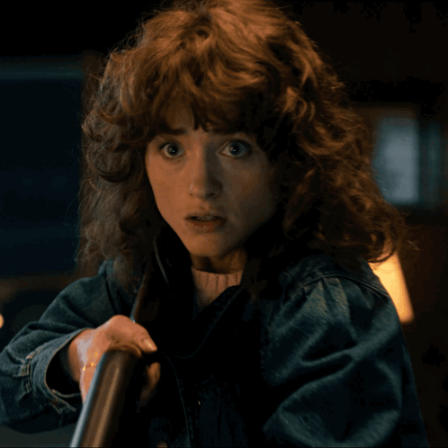 A Woman With Curly Hair And A Denim Jacket GIF