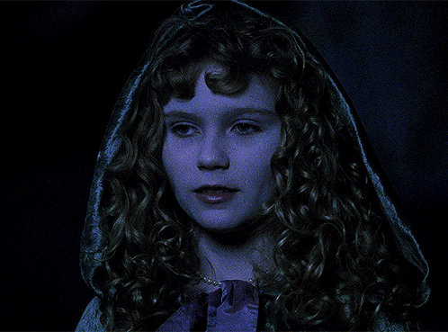 A Woman With Curly Hair And A Hood On Her Head Looks At The Camera GIF