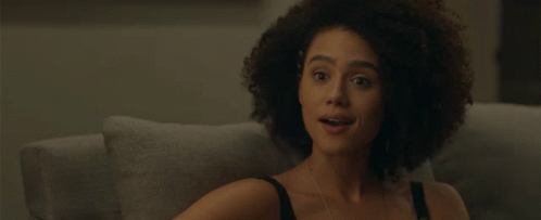 A Woman With Curly Hair Covering Her Mouth With Her Hand While Sitting On A Couch GIF