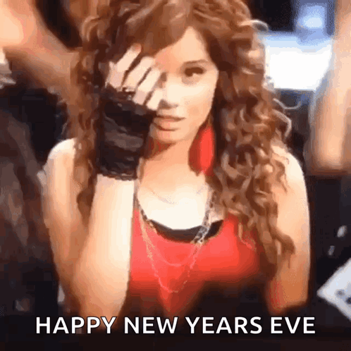 A Woman With Curly Hair Is Covering Her Face With Her Hand And The Words Happy New Years Eve Are Written Below Her GIF