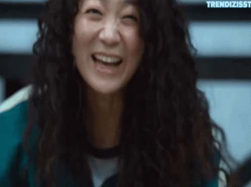 A Woman With Curly Hair Is Laughing And Making A Funny Face . GIF