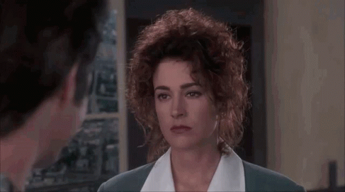 A Woman With Curly Hair Is Looking At A Man In A Room In A Movie . GIF