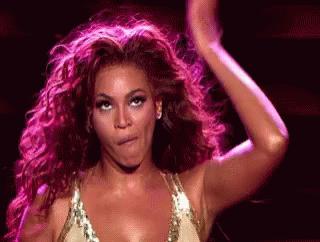 A Woman With Curly Hair Is Making A Funny Face And Dancing On A Stage . GIF