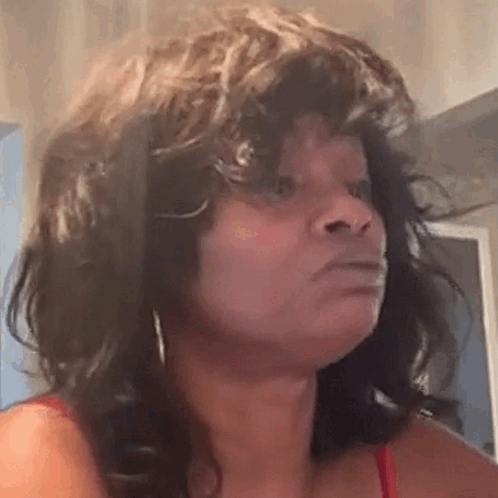 a woman with curly hair is making a funny face and looking at the camera .