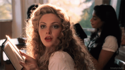 A Woman With Curly Hair Is Reading A Book And The Words Timelordwho Are Visible In The Corner GIF