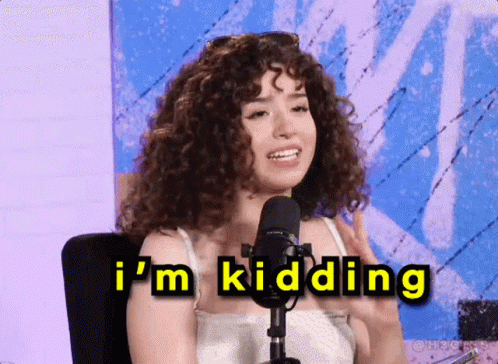 A Woman With Curly Hair Is Sitting In Front Of A Microphone And Says " I 'M Kidding " GIF