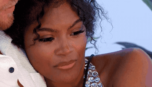 A Woman With Curly Hair Is Sitting Next To A Man In A White Shirt . GIF