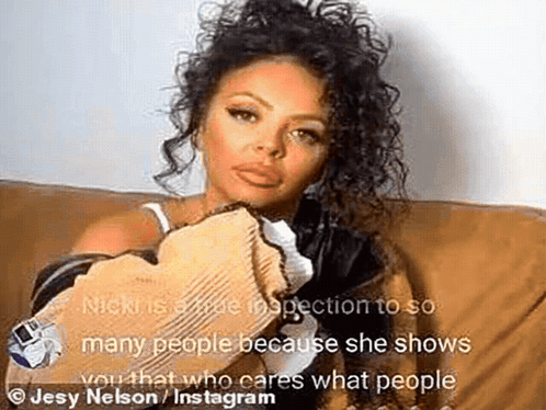 A Woman With Curly Hair Is Sitting On A Couch And Holding A Piece Of Paper . GIF