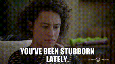 A Woman With Curly Hair Is Sitting On A Couch And Says You 'Ve Been Stubborn Lately .. GIF