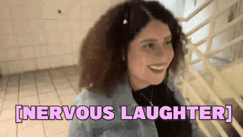 A Woman With Curly Hair Is Smiling And Says Nervous Laughter . GIF