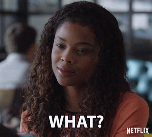 A Woman With Curly Hair Is Smiling And Says " What " GIF