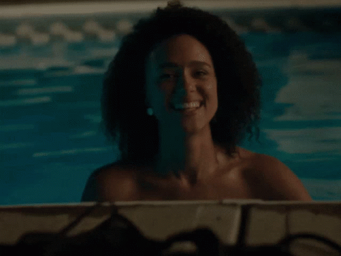 A Woman With Curly Hair Is Smiling In A Pool GIF