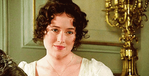 A Woman With Curly Hair Is Standing In Front Of A Candle Holder . GIF