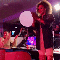 A Woman With Curly Hair Is Standing In Front Of A White Ball GIF