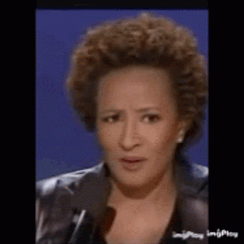A Woman With Curly Hair Is Talking Into A Microphone . GIF