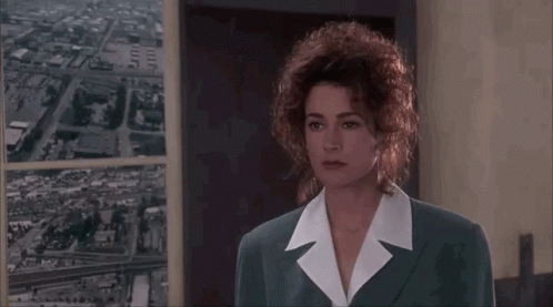 A Woman With Curly Hair Is Talking To A Man In A Suit . GIF