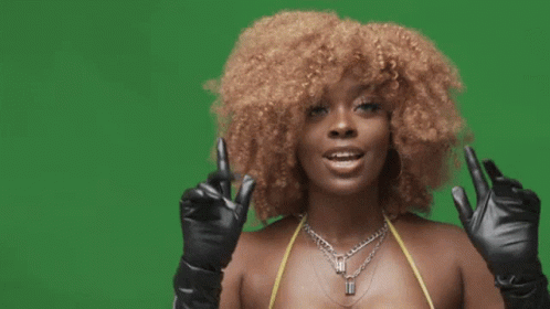 A Woman With Curly Hair Is Wearing A Bikini Top And Black Gloves . GIF