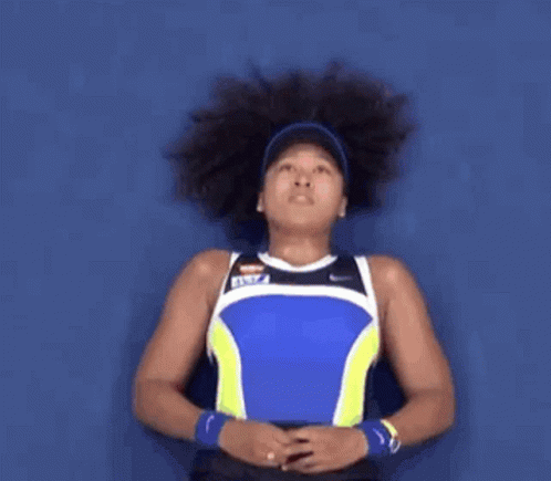 A Woman With Curly Hair Is Wearing A Blue And Yellow Tank Top GIF
