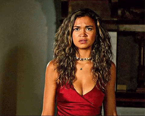 A Woman With Curly Hair Is Wearing A Red Top And A Choker . GIF