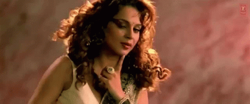A Woman With Curly Hair Is Wearing A Ring On Her Finger . GIF