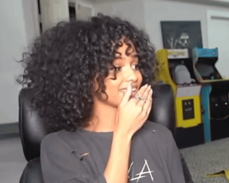 A Woman With Curly Hair Is Wearing A Shirt With The Letter A On It GIF