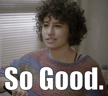A Woman With Curly Hair Is Wearing A Sweater With The Words So Good Written On It GIF