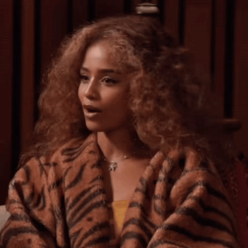 A Woman With Curly Hair Is Wearing A Tiger Print Sweater GIF
