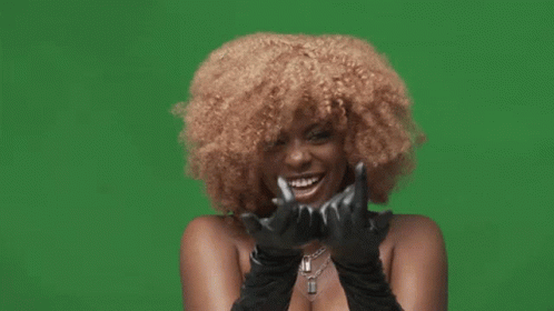 A Woman With Curly Hair Is Wearing Black Gloves And Making A Rock And Roll Sign GIF